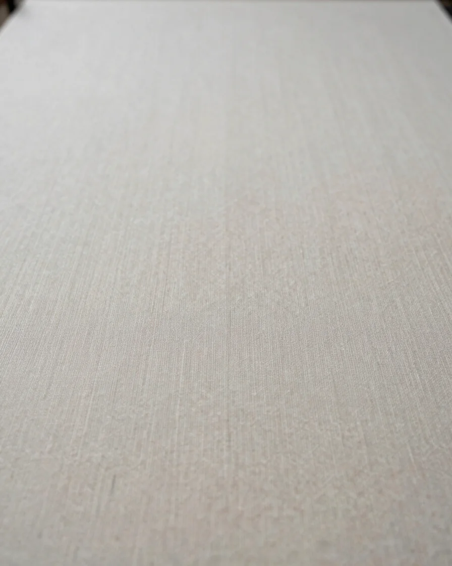 Close documentary detail of textile fabric being handled on a neutral work surface, soft neutral daylight, restrained te